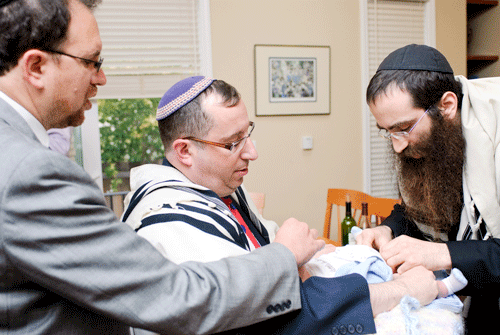 Rabbi Gil Leeds (right) performs a brit mila in Palo Alto, Calif., in July 2010. The baby is being held by Mitchell Ackerson, while Rabbi Yitzchok Feldman looks on. (Photo: Alex Axelrod)
