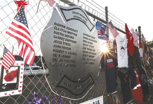 A plaque engraved with names of the 19 fallen firefighters from the Granite Mountain Interagency Hotshot Crew is mounted on a fence outside Station 7, their home base in Prescott, Ariz., on July 3. (Photo: Christian Petersen / Getty Images)