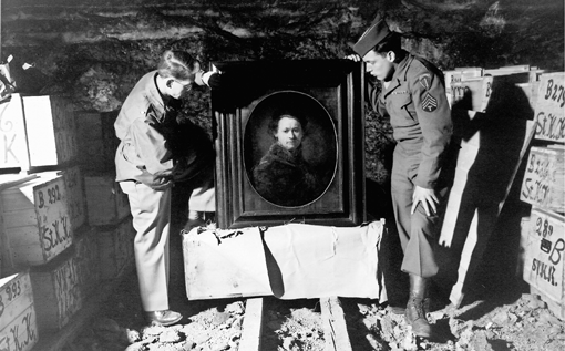 A self-portrait by Rembrandt is inspected by Monuments Men Dale V. Ford (left) and Harry Ettlinger in Heilbronn, Germany, in 1946. The painting was stored for safekeeping by museum officials from Karlsruhe in the Heilbronn mine, and was ultimately returned to the Karlsruhe Museum. This was just one of thousands of paintings and other works of art that were found in Heilbronn, as can be seen by the crates stacked behind each man. (Photo: National Archives and Records Administration, College Park, Md.)