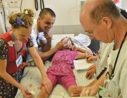 Penny Hanuka (left) does “mirror work,” copying a doctor’s movements, during a joint injection on a young patient at Meir Medical Center in Kfar Saba, Israel. (Photo: Courtesy of Dream Doctors Project)