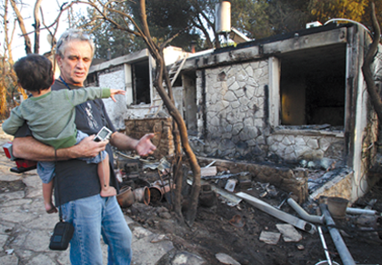 A father and his son look at the remains of their house in Ein Hod, near Haifa, on Sunday. About 250 houses burned down in the Carmel Forest fire. (Photo: Meir Partush/Flash90/JTA)